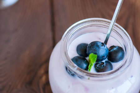 Close up of fresh blueberry yogurt in a jar on a wooden table.の写真素材