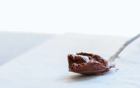 Melted chocolate paste in a spoon on a whte stone background. Close up and copy space.の写真素材
