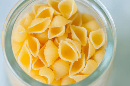 Raw pasta in a glass jar. White background.の写真素材
