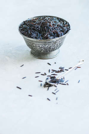 Black long rice on a bowl on a white stone background. Toned, copy space.の写真素材