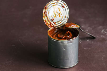 Caramel condensed milk in can on a brown background.の写真素材