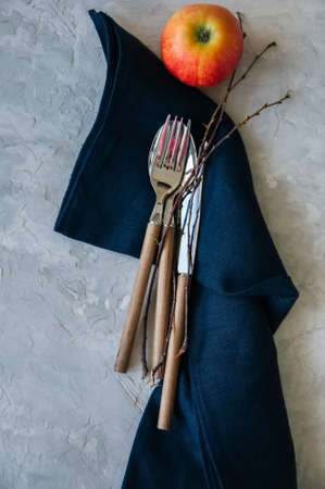 White plate, red apple and brunches and blue linen napkin on a wooden background. Autumn, Thanksgiving, Halloween concept.の写真素材