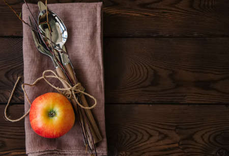 Tree branches apple cutlery on a linen sackcloth on a wooden background.の写真素材