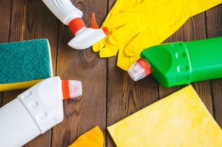 Cleaning concept. Sprays and rubber gloves on a wooden background