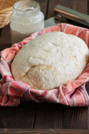Homemade dough, sourdough in a jar, mix of flours, bread and basket for proof and spatula on a wooden background. Baking concept.の写真素材