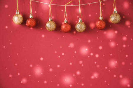 Red and Gold Christmas Balls haning on rope on red background. Xmas Decorations.Toned.  Selective...