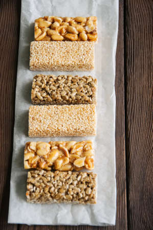 Snacks  - mix of energy bars with peanut, sesame and sunflower seeds on a wooden backgroundの写真素材
