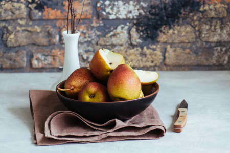 Ripe pears in a plate on a white stone background. Toned.の写真素材