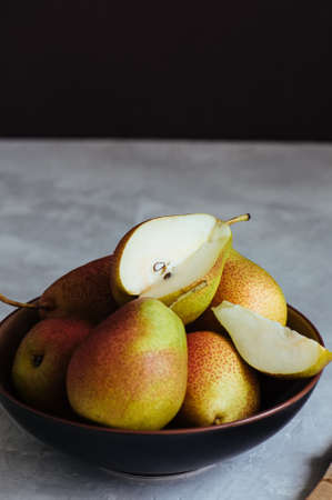 Ripe pears in a plate on a white stone background. Toned.の写真素材