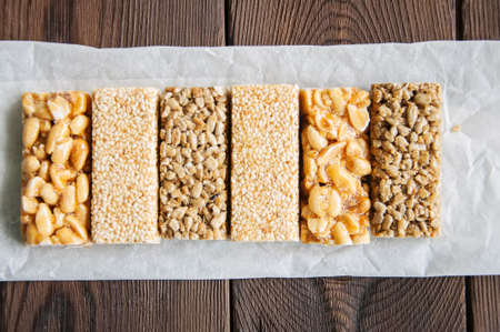 Snacks  - mix of energy bars with peanut, sesame and sunflower seeds on a wooden backgroundの写真素材