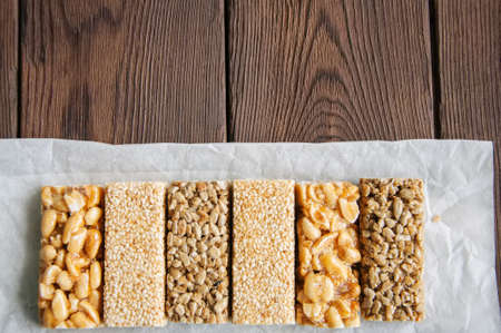 Snacks  - mix of energy bars with peanut, sesame and sunflower seeds on a wooden backgroundの写真素材