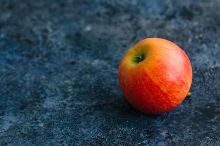 One red ripe apple on a blue stone backgroundの写真素材
