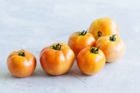 Orange fresh ripe tomatoes on a white stone background. Top view and copy space.の写真素材