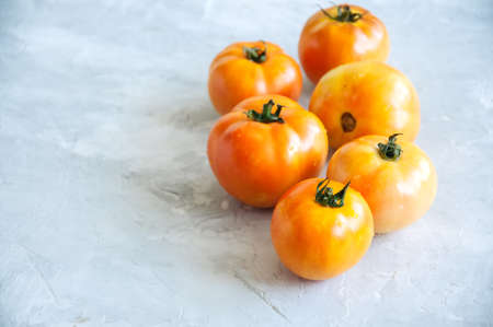 Orange fresh ripe tomatoes on a white stone background. Top view and copy space.の写真素材