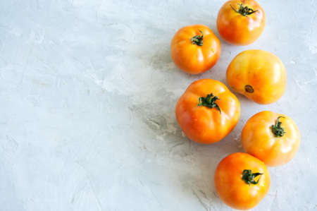 Orange fresh ripe tomatoes on a white stone background. Top view and copy space.の写真素材