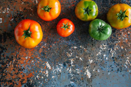 Different sizes of colorful fresh tomatoes on a rusty background. Top view and copy space.の写真素材