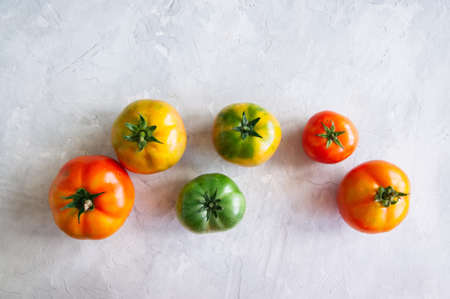 Different sizes of colorful fresh tomatoes on a white stone background. Overhead view and copy space.の写真素材