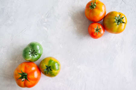 Different sizes of colorful fresh tomatoes on a white stone background. Overhead view and copy space.の写真素材