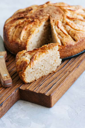 Easy apple tea cake on a wooden board. White stone background. Homemade baking.の写真素材