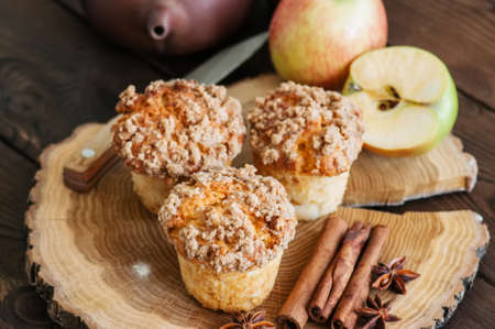 Apple cinnamon crumble muffins, spices and half of apples on a wooden board. Wooden background. Close up and copy space.の写真素材