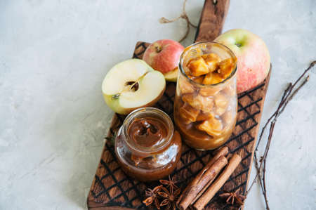 Ingredients for traditional apple pie- salted caramel, slices of apple in caramel sauce, cinnamon sticks on a wooden board. White stone background and close up.の写真素材