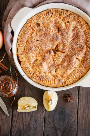 Traditional American apple pie in a ceramic form and ingredients on a wooden table. Close up and overhead view.の写真素材