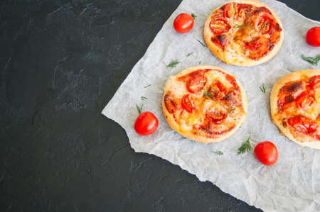 Mini pizzas margheritas on a parchment paper on a black stone background. Top view with copy space.の写真素材
