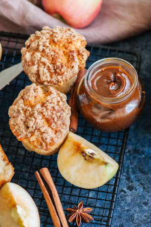 Apple crumb muffins, salted caramel in a jar served on a wire rack on a blue stone background. Close up.の写真素材