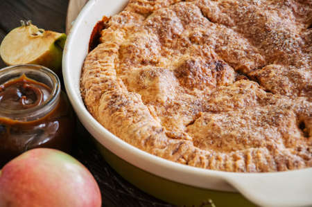 Traditional American apple pie in a ceramic form and ingredients on a wooden table. Close up and overhead view.の写真素材