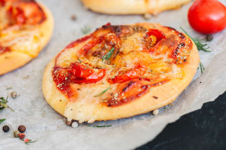 Mini pizzas margheritas on a parchment paper on a black stone background. Top view with copy space.の写真素材