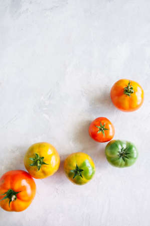Different sizes and colors of fresh tomatoes on a white stone background. Top view and copy space.の写真素材