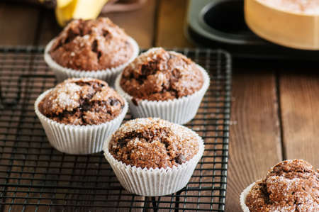 Homemade banana chocolate muffins sprinkled with sugar on a wooden background.の写真素材
