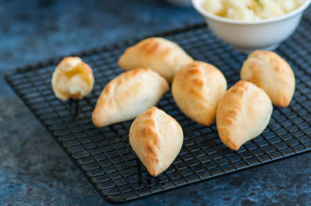 Small mashed potato pasties (hand pies) in a wire rack. Blue stone background.の写真素材