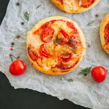 Mini pizzas margheritas served on a baking paper. Black stone background.の写真素材