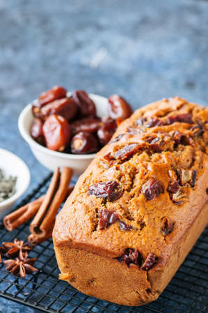 Honey and date spicy cake serving on a wire rack. Blue stone background.の写真素材