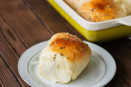 Homemade all-dinner rolls with mozzarella cheese and oregano on a wooden background.