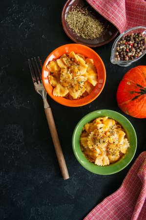 Pumpkin creamy mac and cheese baked pasta over black stone background. Comfort food.の写真素材