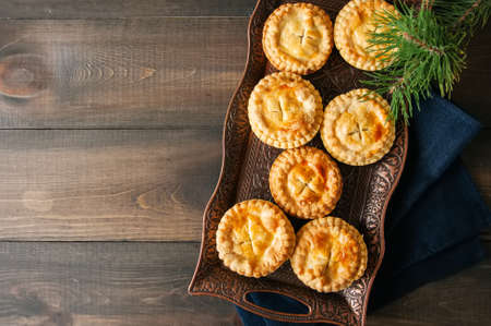 Mini meat pies from flaky dough on a vintage tray over wooden background.の写真素材