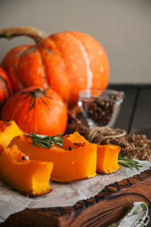 Roasted pumpkin slices with rosemary and dry thyme on a baking paper on a wooden background.の写真素材
