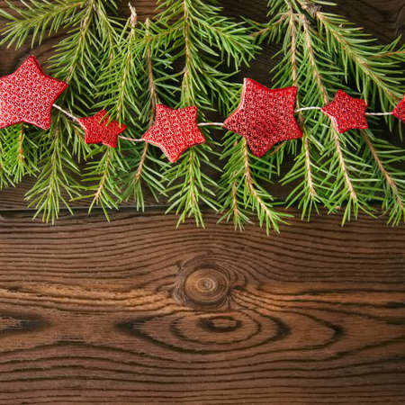 Christmas backdrop. Fir tree branches and red star garland on a wooden background.の写真素材