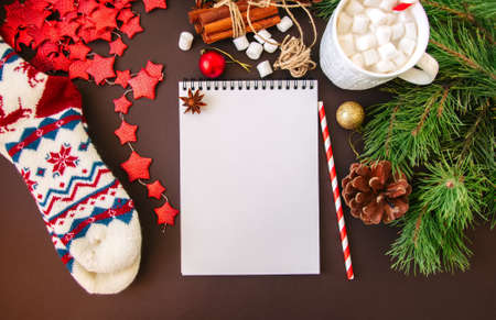 Christmas background with white empty page of notebook, red star garland, chocolate with...