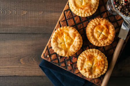 Mini meat pies from flaky dough on a wooden board over wooden background.の写真素材