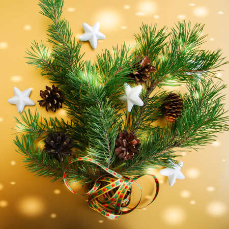 Fir tree branches with cones and stars over golden background, Festive decoration. Square image.の写真素材