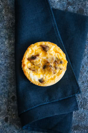 Savory mini tart. Quiche with mushrooms. Blue stone background.