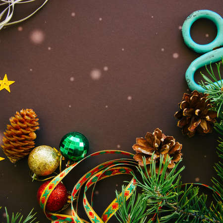 Festive Christmas backdrop with fir tree branches, cones, stars and  decorative ribbons over brown background. Square image.の写真素材