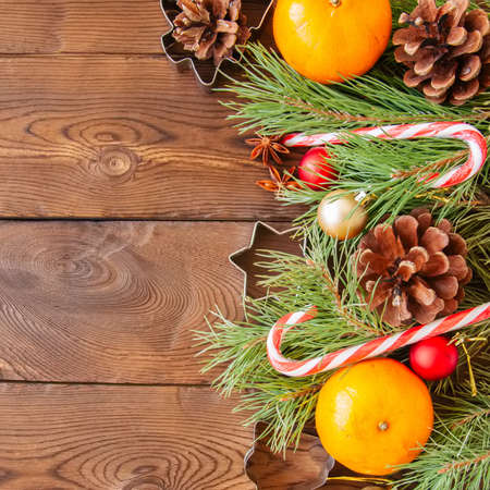 Christmas decoration. Background with fir tree branches, oranges, candy canes and cookie cutters. Wooden backdrop.の写真素材