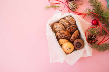 Christmas cookies gift box. Homemade festive baking concept, fir tree branches, balls. Pink background and overhead view.の写真素材
