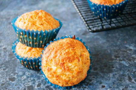 Homemade apple cheese muffins on a wire rack. Blue stone background. Seasonal baking.の写真素材