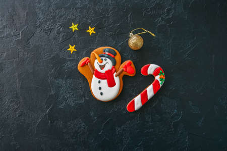 Festive Christmas background, Cookies with image of Snowman, candy cane,  stars and ball on a black stone background. Top view with copy space.の写真素材
