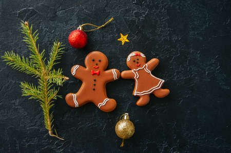 Christmas background. Gingerbread man and girl cookies, fir tree, balls on a black stone background. Top view.の写真素材